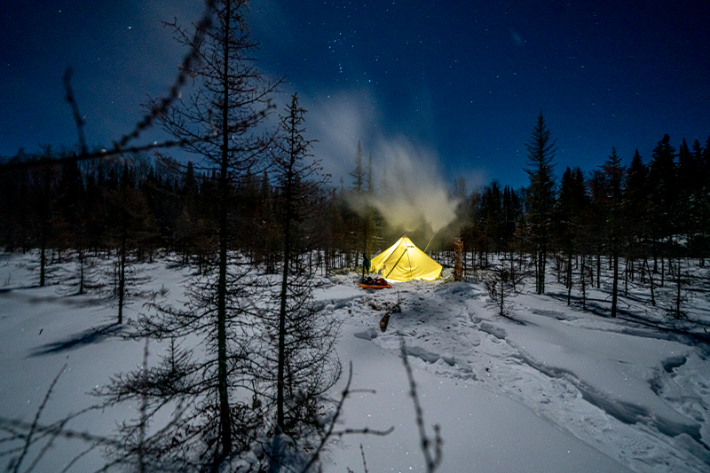 a glowing esker tent under the night sky