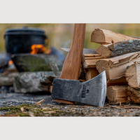 Esker Camp Axe leaning against a stack of firewood with a blurred background