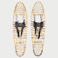 Pair of traditional snowshoes, with leather bindings on a light grey background 