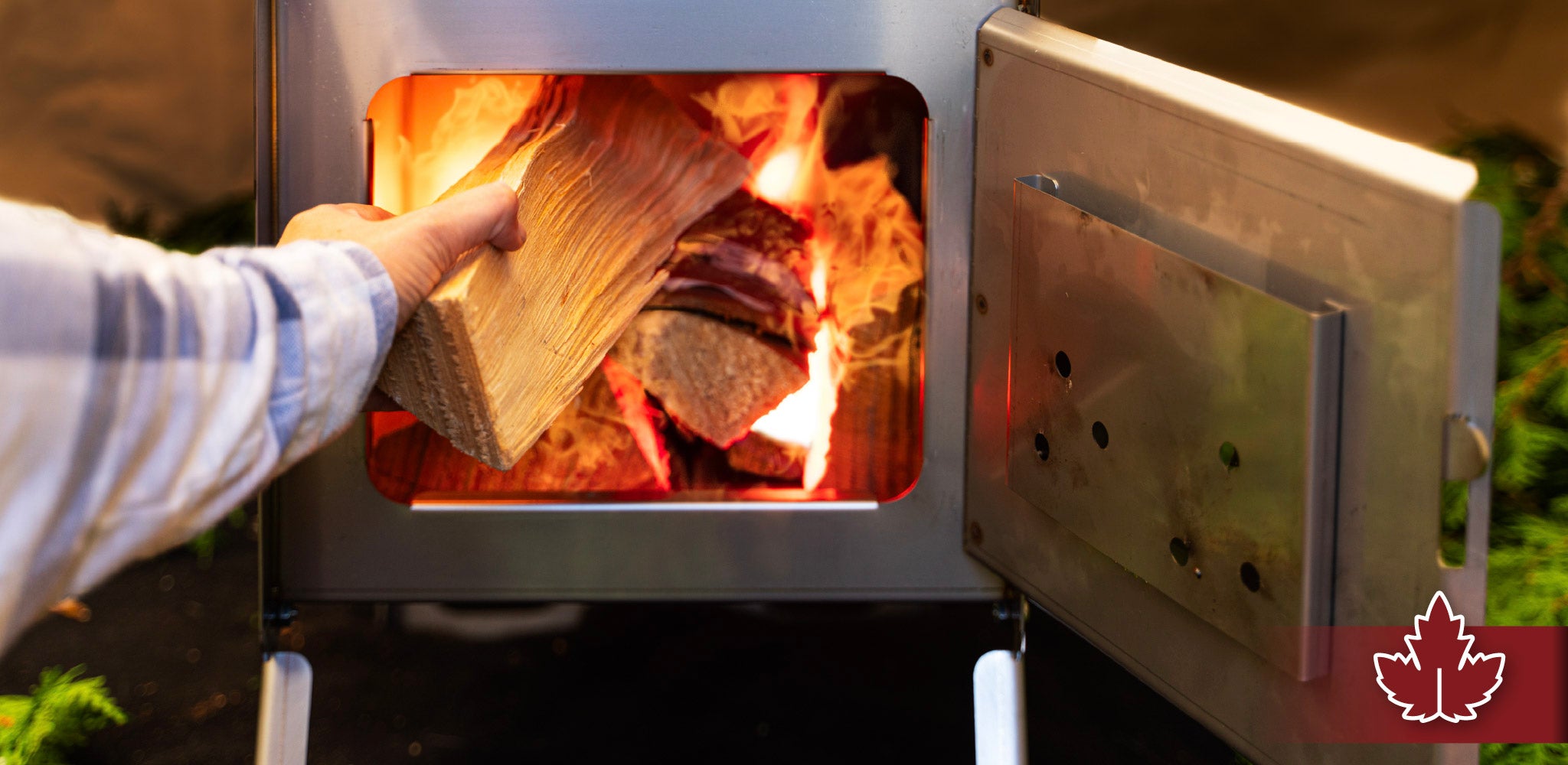Person loading wood into a Esker stove for winter camping.
