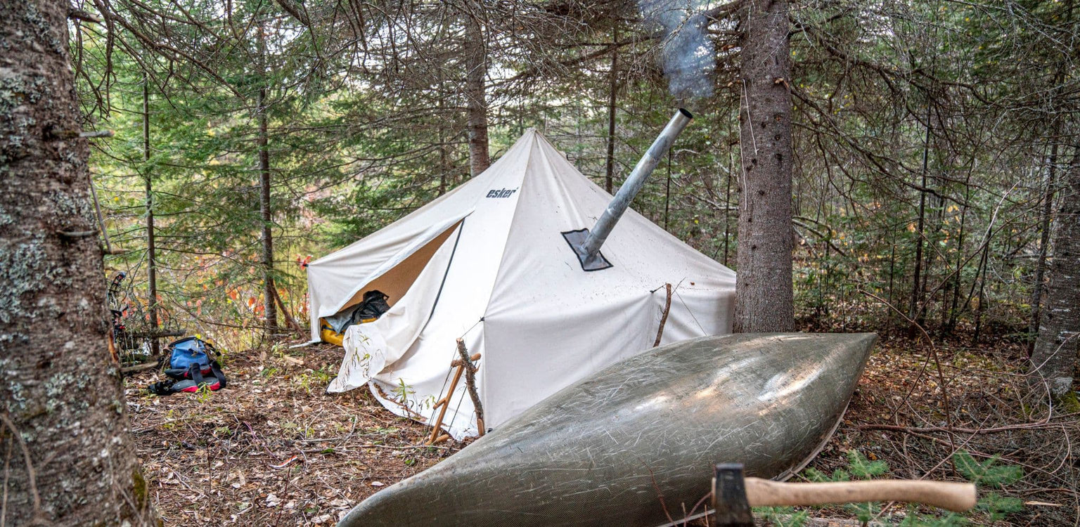 Esker canvas hot tent set up in backcountry with no snow in the ground.