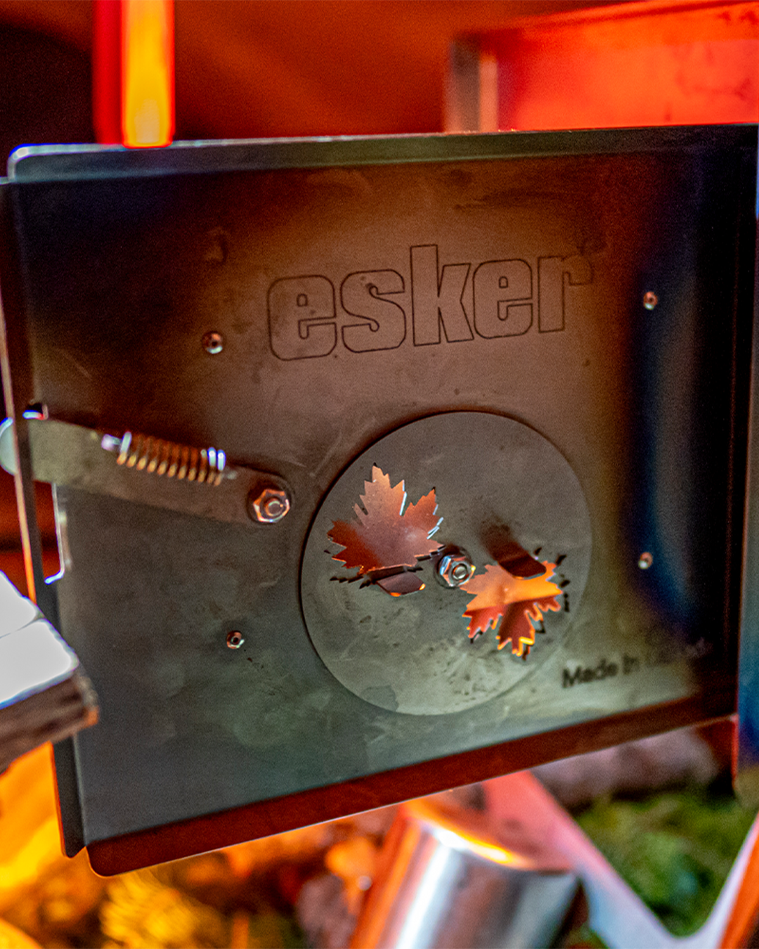 the door of an Canadian made esker stove open, with a glow behind it from the fire.