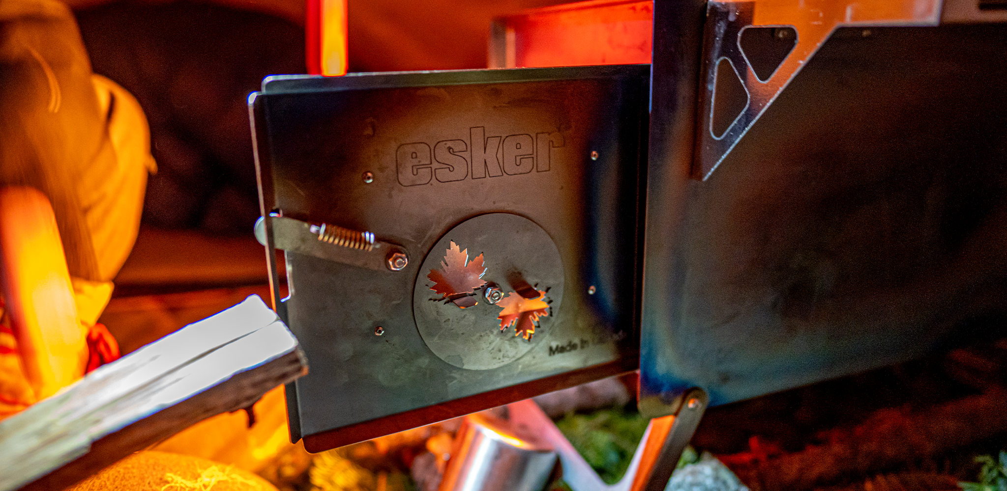 the door of an canadian made esker stove open, with a glow behind it from the fire.